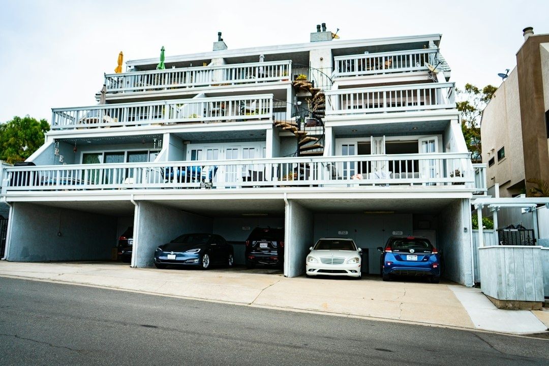Flerbostadshus med balkonger och bilar parkerade under huset